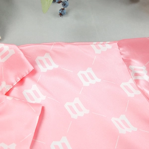 Detail of pink satin sleepwear fabric with white geometric pattern and smooth texture