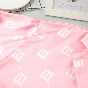 Detail of pink satin pajamas showing silky fabric texture and gothic letter print
