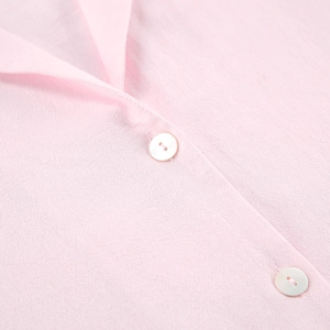 Détail du col de pyjama en coton rose avec boutons nacrés et bords volantés