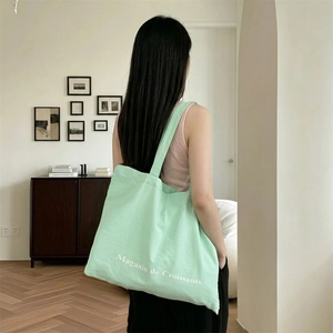 Detalle del bolso tote de lona verde claro con estampado Magasin de Croissants al hombro