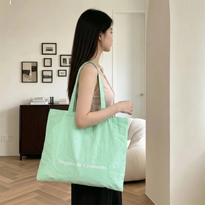 Detalle del bolso tote de lona verde menta con estampado Magasin de Croissants estilo de vida