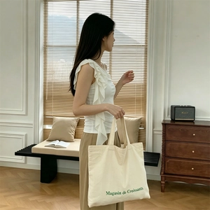 Bolso tote de lona con estampado francés llevado por modelo en un salón elegante