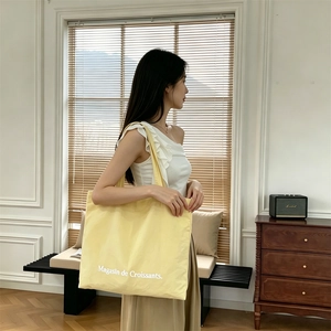 Bolso tote grande de lona beige con estampado 'Magasin de Croissants' en escena de estilo de vida