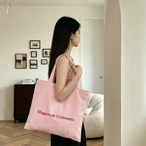 Detalle del bolso tote de lona rosa con el estampado Magasin de Croissants y la correa