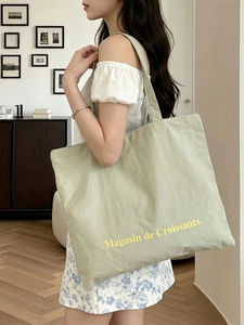 Large capacity green canvas tote bag with croissant print shown on model for daily use