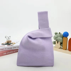 Close-up of light purple knitted handbag with soft texture and minimalist knot design