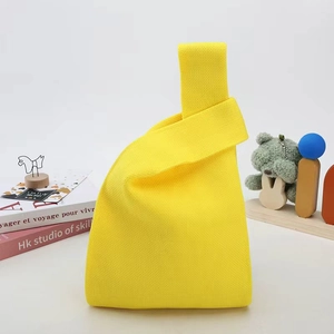 Detail of a bright yellow knitted knot bag showing premium woven texture and minimalist design
