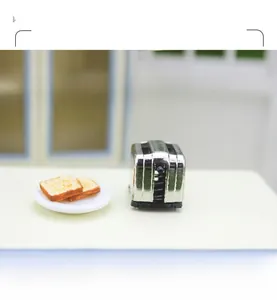 Macro view of a miniature silver toaster model with toast slices on a white ceramic plate