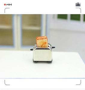Macro view of silver dollhouse miniature toaster model with two slices of toast inside