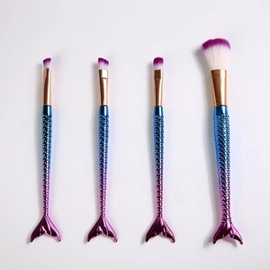 Detailed view of four mermaid makeup brushes with purple synthetic bristles and gradient fish-tail handles