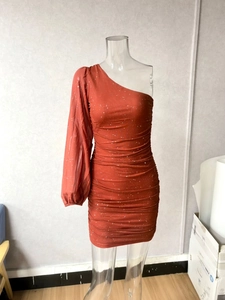 Detail view of the rust red sequined dress showing ruched fabric and one-shoulder lantern sleeve
