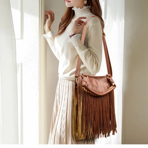 Bohemian brown tassel crossbody bag with gold studs shown on a fashion model