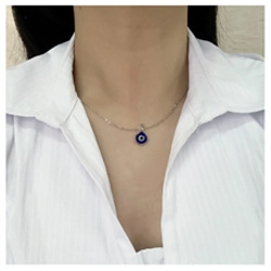 Gros plan détaillé du collier pendentif œil bleu turc sur une chemise à rayures