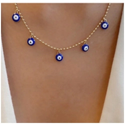 Détail d'un collier doré avec cinq breloques œil de démon bleues porté par un mannequin