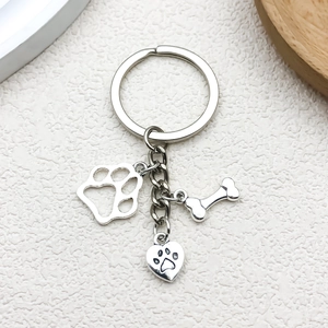 Detailed close-up of a silver pet memorial keychain with paw print and bone charms