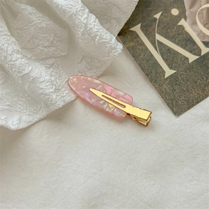 Elegant pink marble acetate hair clip with golden metal base on lace background