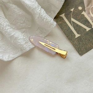 Elegant purple marble acetate hair clip with golden metal grip on white fabric
