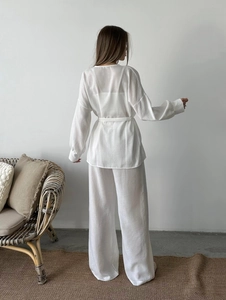 Vue de dos de l'ensemble de détente blanc en coton avec haut ceinturé et pantalon large