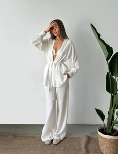 Détail de la texture d'un ensemble trois pièces en lin blanc avec cardigan et pantalon