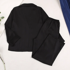 Vue à plat d'un pyjama noir en satin montrant le haut à manches longues et le pantalon fluide