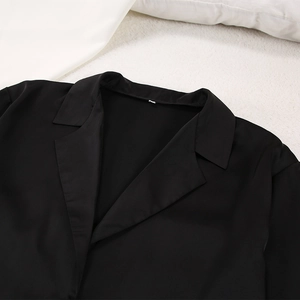 Vue détaillée du haut de pyjama en satin noir avec col à revers sur fond en peluche blanc