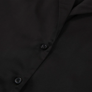 Détail du revers et des boutons noirs à quatre trous sur l'ensemble pyjama en soie
