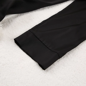Détail des poignets de pyjama en satin noir avec coutures précises sur peluche blanche