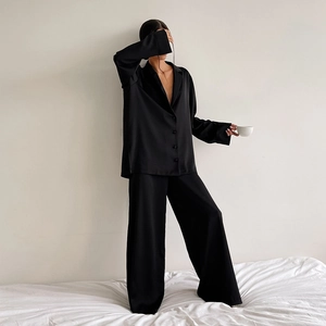Détail d'un pyjama élégant en satin noir avec chemise boutonnée et pantalon large