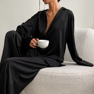 Gros plan d'un pyjama en satin noir montrant une texture soyeuse sur un canapé blanc