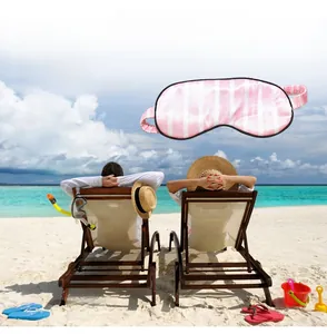 Detail of pink striped sleep mask with black embroidered text on a sunny beach background