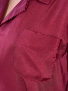 Close-up of wine red satin pajama top with lapel collar and pocket stitching details