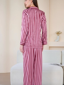 Detail view of pink vertical striped satin pajamas for women in a cozy home setting