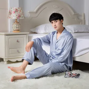 Detail of light blue satin men's pajamas with white contrast piping and chest pocket embroidery