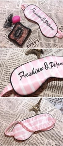 Detailed view of pink striped satin sleep mask with black Fashion & Pajamas embroidery