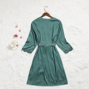 Détail d'un peignoir en satin vert foncé avec dentelle aux manches et ceinture à nouer