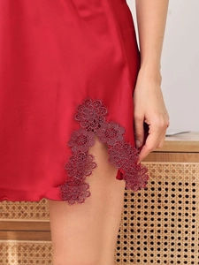Détail de la nuisette en satin rouge foncé avec fente latérale et broderie en dentelle