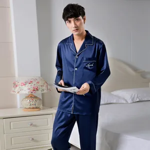 Detail of dark blue satin men's pajama set featuring classic lapel and pocket embroidery