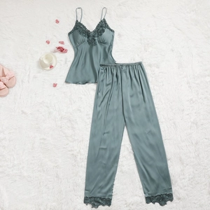 Détail d'un pyjama en satin vert sauge avec dentelle florale sur fond en peluche