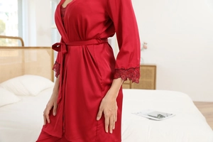 Detail of red silk robe with black lace cuffs and tie belt in a modern bedroom setting