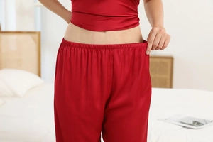 Detail of the elastic waistband on wine red silk pajamas showing stretch and soft fabric