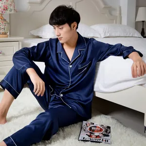 Detail of white cursive embroidery on the chest pocket of navy blue satin pajamas