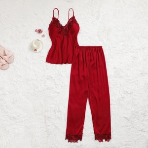 Détail du pyjama en satin rouge avec dentelle délicate sur un tapis en fausse fourrure