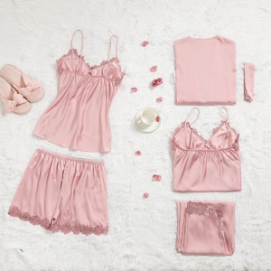 Ensemble homewear en satin rose avec bordure en dentelle et accessoires sur tapis en fourrure