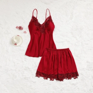 Détail du pyjama deux pièces en satin rouge avec dentelle noire sur tapis blanc doux