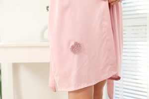 Détail d'un peignoir en satin rose avec broderie florale en dentelle et une ceinture