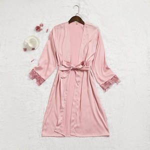 Peignoir en satin rose avec manches en dentelle et ceinture sur fond en fausse fourrure