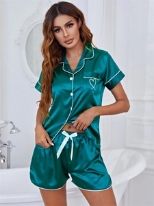 Détail de pyjama en satin avec poche à motif cœur et finitions liserés blancs