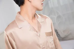 Detail of champagne gold satin pajama top with lapel collar and chest pocket embroidery