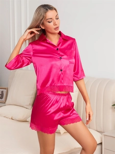 Close-up of pink satin pajama set featuring delicate lace trim and black buttons