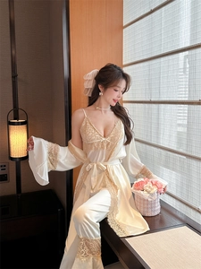 Detail of white satin camisole with golden lace trim and elegant lounge robe set